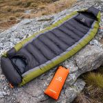 brown and black heated sleeping bag on rocks camping